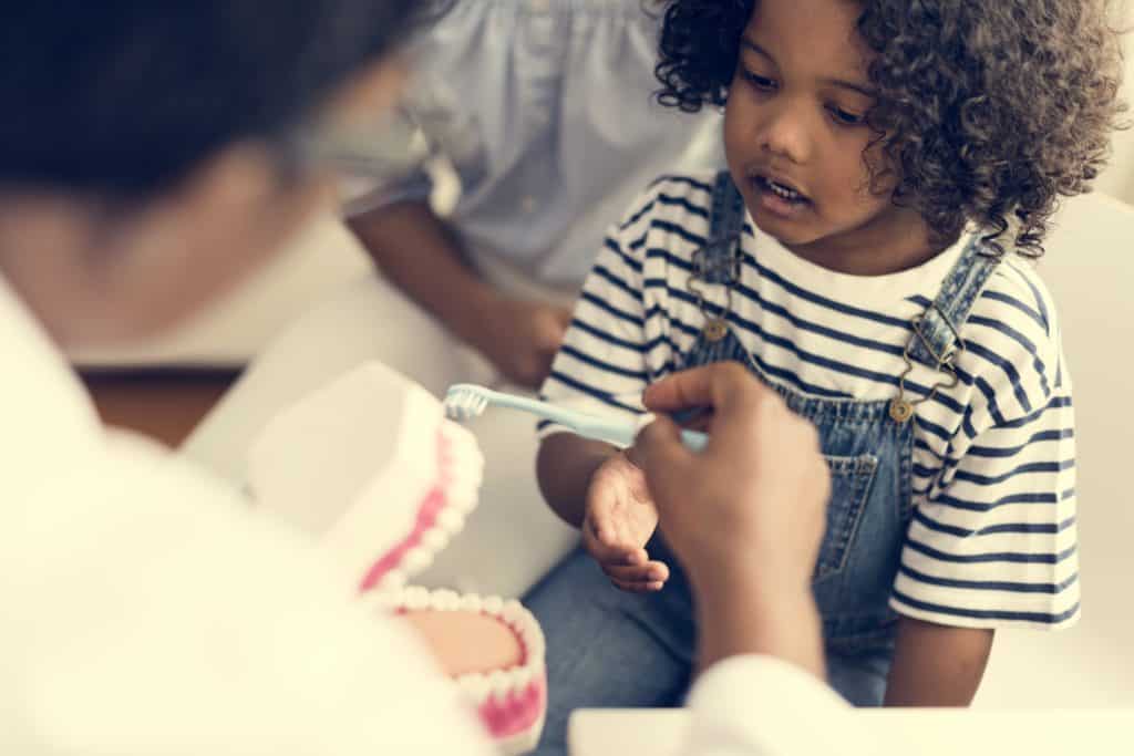 young african kid with a dentist P2GHRVC 1024x683 - What Age Should I Take My Child to the Dentist?